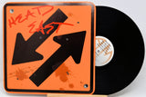An orange square vinyl record sleeve or art print with black arrows, red graffiti-style text reading 'HEAD EAST,' and orange paint splatter details, shown next to a black vinyl record on a white background.