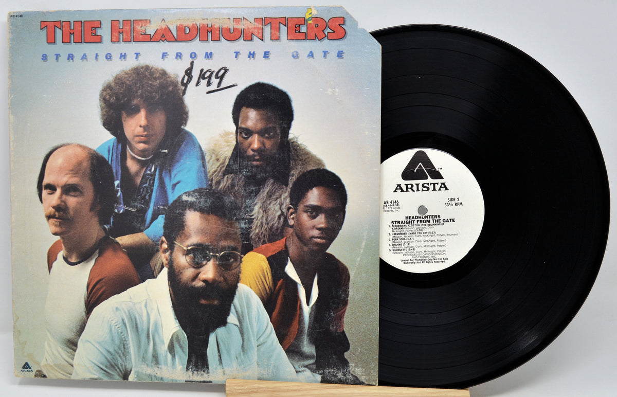 The Headhunters 'Straight From The Date' vinyl record with the album cover on the left and the black LP record partially visible on the right. The cover features a group portrait of five men, with the band name in red at the top and an Arista label on the record center.