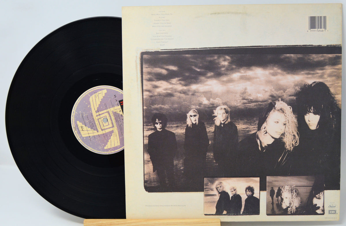 A vinyl record partially pulled from its sleeve, showing the black record and the back cover artwork with a sepia-toned band photo and small inset photos on a light background.