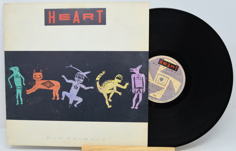 A vinyl record and its sleeve for the band Heart's 'Had A Rime Like A Song' are shown on a light background. The sleeve features a cream border with a black central panel containing stylized colorful animal figures, and the record itself is black with a matching label.