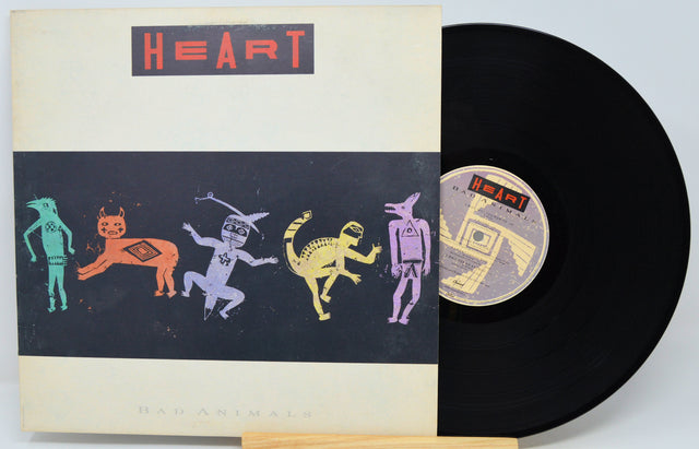 A vinyl record and its sleeve for the band Heart's 'Had A Rime Like A Song' are shown on a light background. The sleeve features a cream border with a black central panel containing stylized colorful animal figures, and the record itself is black with a matching label.