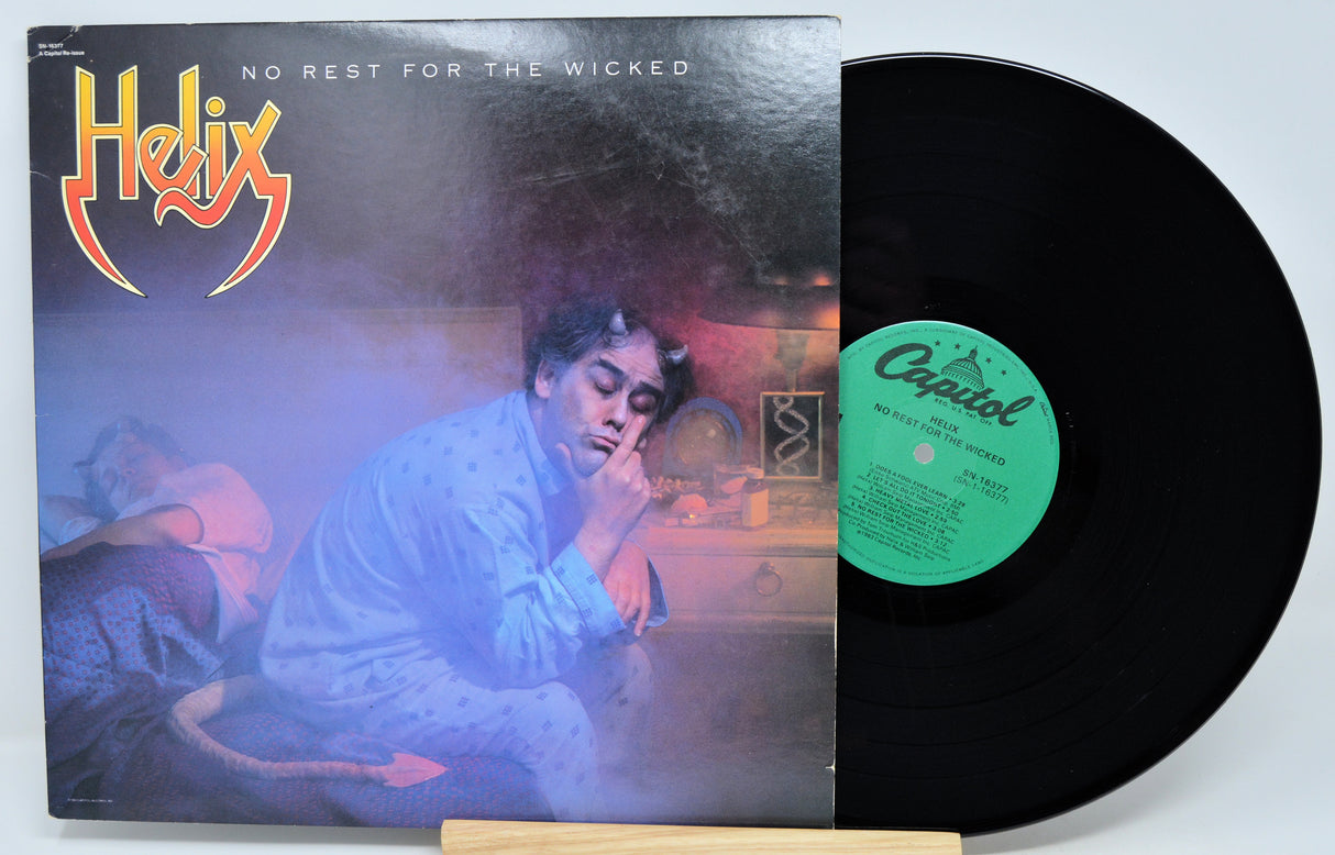 Helix - No Rest For The Wicked vinyl record LP with the album cover standing beside the black record on a small wooden stand.