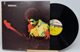 Vinyl record with a colorful cover featuring a person playing guitar, on a white background.