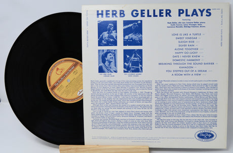 Vinyl record with its cover displaying 'Herb Geller Plays' on a white background