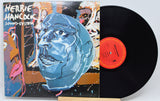 Hellrie Hancock's 'Sound-System' vinyl record LP with its illustrated cover jacket and a black vinyl disc partially visible, displayed on a small wooden stand against a light gray background.