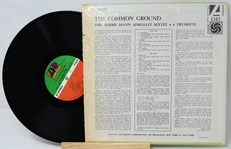 Vinyl record with cover displaying text and a logo on a white background