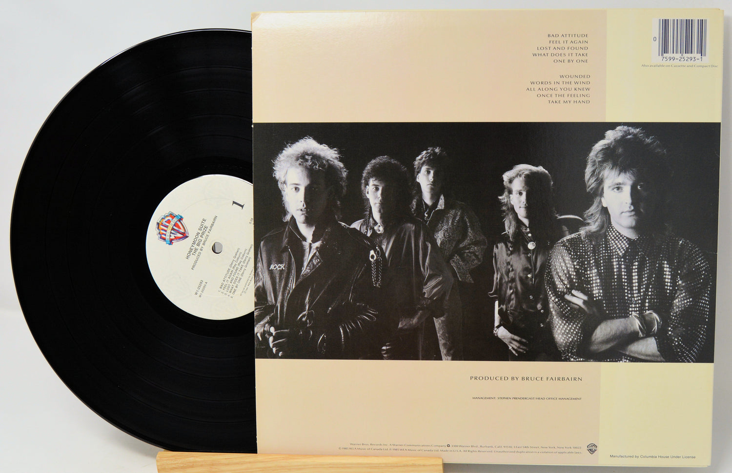 A vinyl record partially pulled from its sleeve, showing the black record and the cream-colored back cover with a black-and-white band photo and track listing.