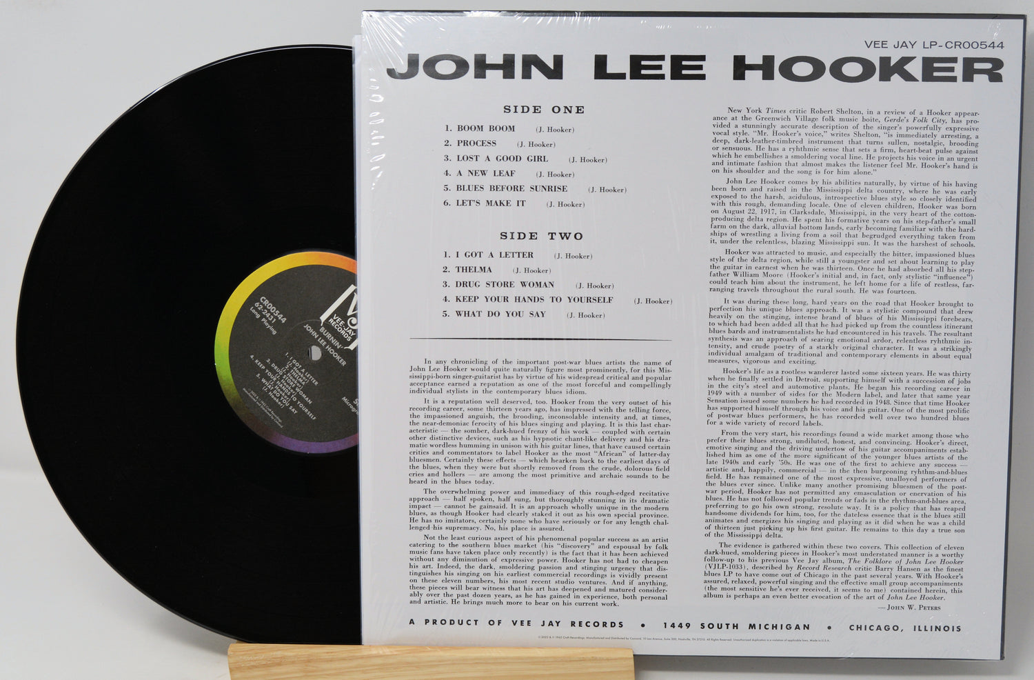A vinyl record partially pulled from its sleeve, showing the black record on the left and the printed inner sleeve track listing on the right. The sleeve reads 'JOHN LEE HOOKER' and 'VIE JAY LP-CRS0054'.