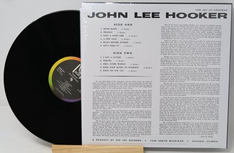 A vinyl record partially pulled from its sleeve, showing the black record on the left and the printed inner sleeve track listing on the right. The sleeve reads 'JOHN LEE HOOKER' and 'VIE JAY LP-CRS0054'.