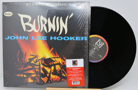 Vinyl record album 'Burnin'' by John Lee Hooker, shown with the black LP partially pulled from the sleeve. The sleeve features a fiery graphic and the artist's name in blue text.
