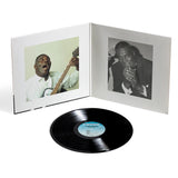 Vinyl record with a white cover featuring black and white photos of a musician playing guitar and singing.