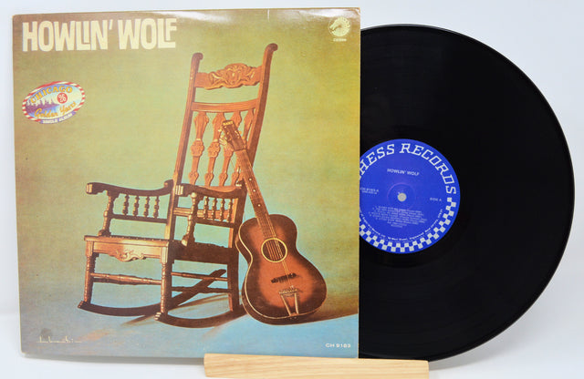 Vinyl record with a guitar and chair on the cover, featuring Howlin' Wolf, on a white background.