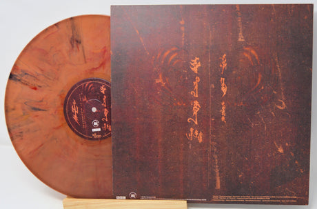 Vinyl record with orange-brown disc and matching cover on a white background