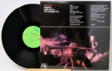 Vinyl record and its cover featuring a person with a rifle and smoke, with 'Red Clay' and 'Delphiia Suite Sioux' text.
