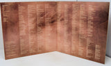 Folded bronze plaque with engraved text on a white background