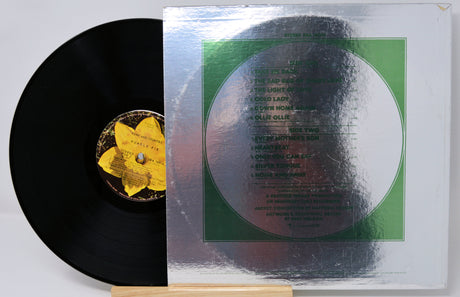 A vinyl record partially pulled from its sleeve, showing the black record with a yellow flower center label beside the white cover featuring a large green circular design and tracklist text.