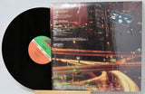 Vinyl record with cover featuring a cityscape at night.