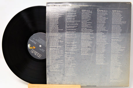 Vinyl record with a clear sleeve displaying track listings on a white background