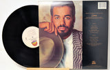 A vinyl record album shown with the black record partially pulled from its sleeve, featuring a portrait of a man on the front cover and track listing text on the back, photographed on a white background.