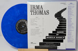 A blue translucent vinyl record partially tucked behind its printed album cover for Irma Thomas's 'Down at Muscle Shoals.' The cover shows black text and staircase graphics on a white background, with the Chixx / Gress label branding visible.