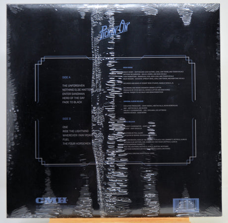 The back cover of a vinyl record album wrapped in protective plastic, featuring a black background with white text and track listings.