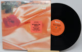 Vinyl record with cover featuring a rose and text, on a white background