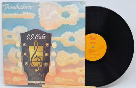 Vinyl record with a guitar-shaped album cover featuring J.J. Cale on a light blue background.