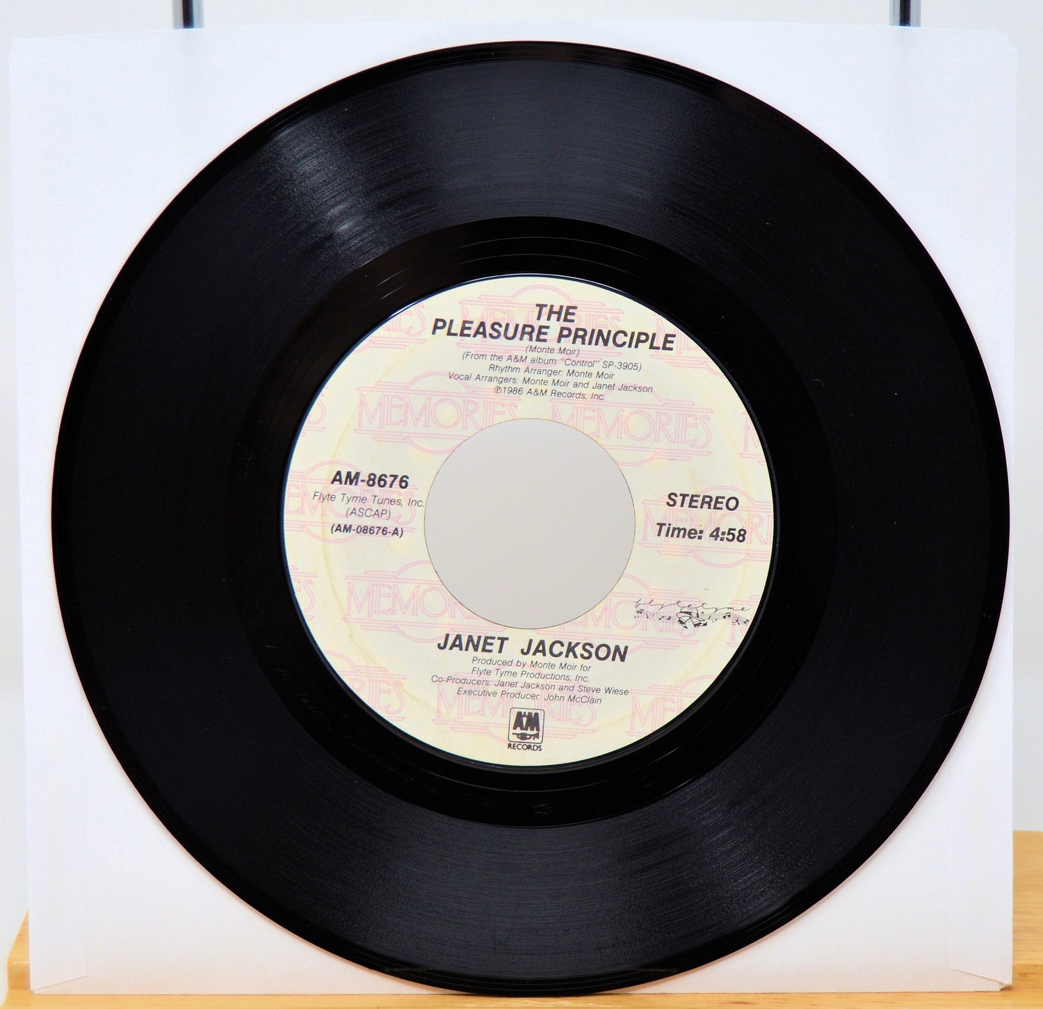 Vinyl record with 'The Pleasure Principle' by Janet Jackson on a white background