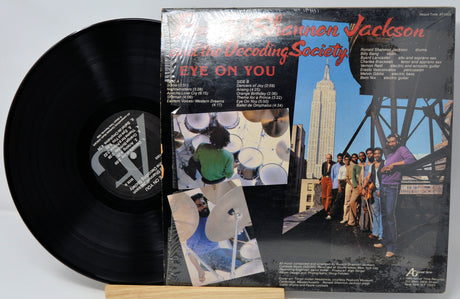 Vinyl record with its cover featuring a group of people and a building.