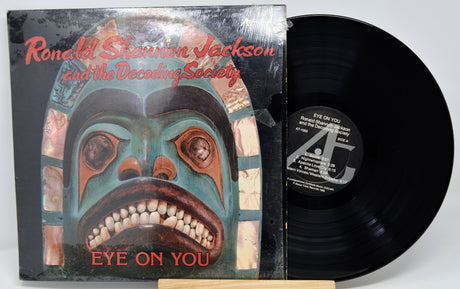 Vinyl record with cover featuring a stylized face design and text.