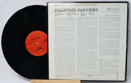 Vinyl record with red label and white text cover on a light gray background