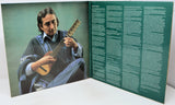 Album cover with a person playing guitar on one side and text on the other, on a white surface.