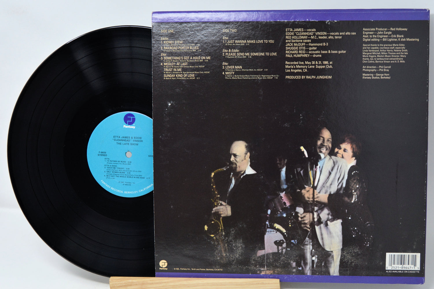 Vinyl record with cover featuring a band on stage, on a light gray background