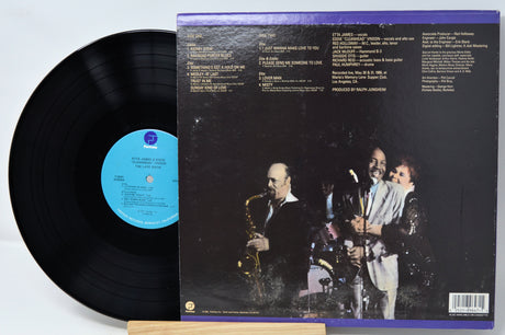 Vinyl record with cover featuring a band on stage, on a light gray background