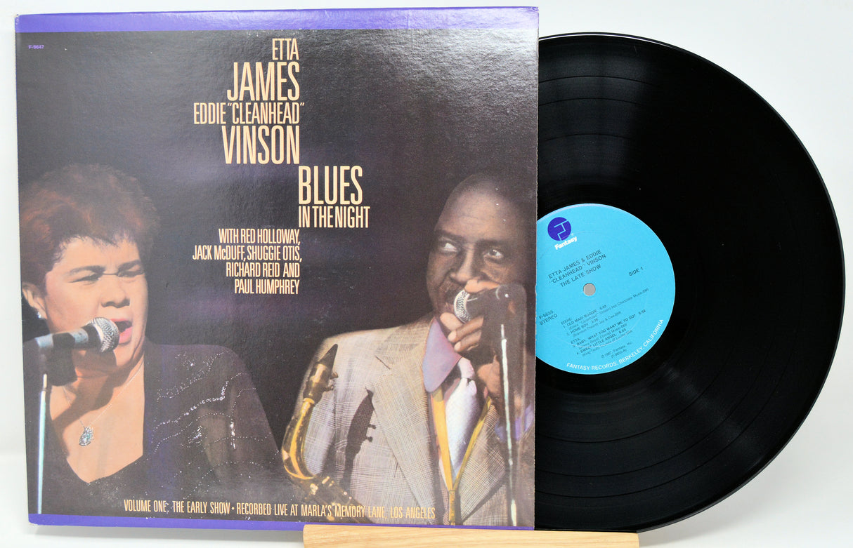 Vinyl record with cover featuring two individuals singing into microphones, on a white background.