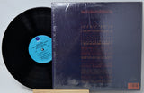 Vinyl record with a blue label and its cover on a gray background