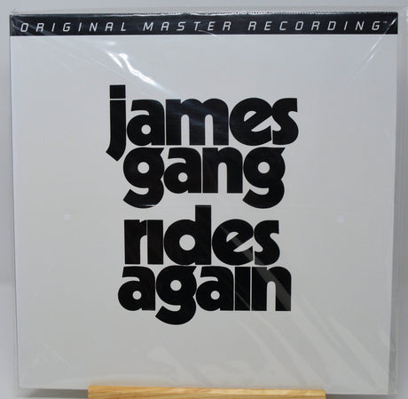 James Gang - 'Rides Again' original master recording vinyl LP cover, sealed in plastic shrink wrap and displayed on a wooden stand against a white background.