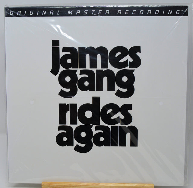 James Gang - 'Rides Again' original master recording vinyl LP cover, sealed in plastic shrink wrap and displayed on a wooden stand against a white background.