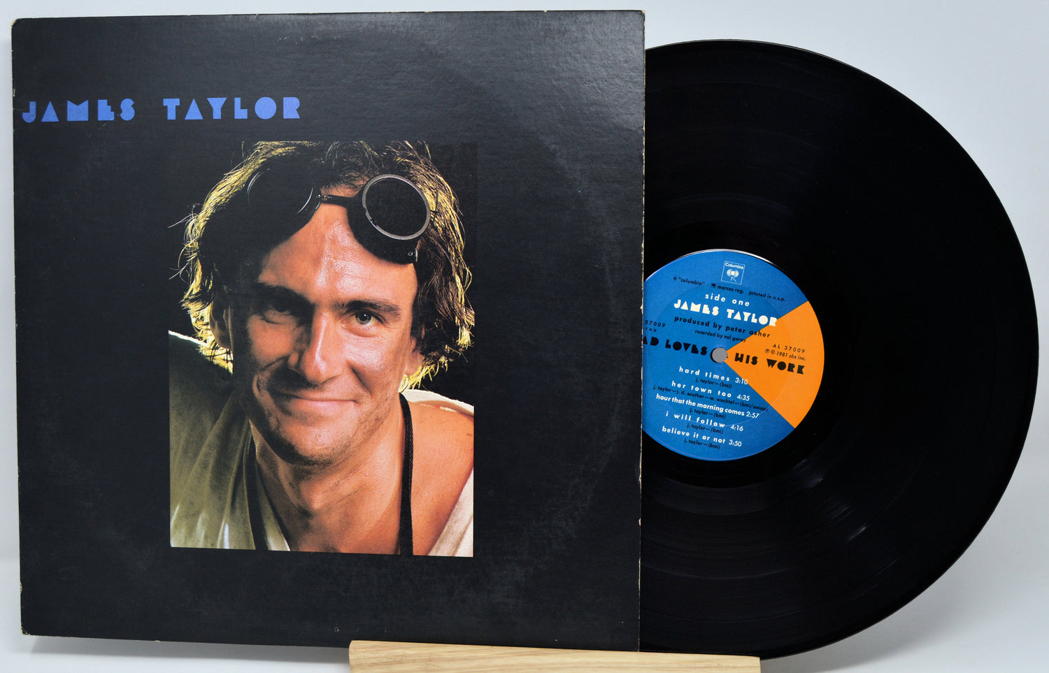 James Taylor 'This Is My Work' vinyl record with the black album cover standing next to the black vinyl disc on a small wooden display stand.