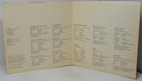 An open vintage songbook or printed booklet with cream-colored pages and black printed text, photographed against a light neutral background.