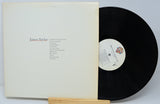 Vinyl record with a wooden holder and white cover displaying 'James Taylor' on a light gray background