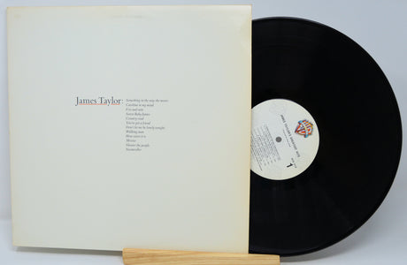 Vinyl record with a wooden holder and white cover displaying 'James Taylor' on a light gray background