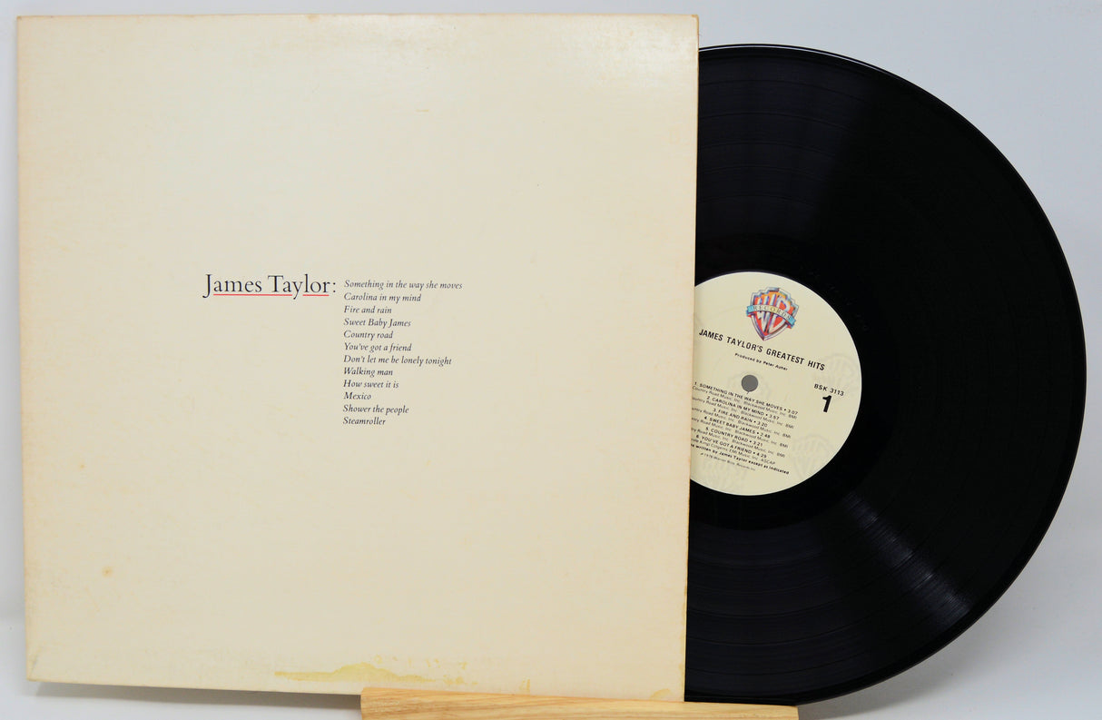 James Taylor vinyl record album with the sleeve partially pulled back to reveal the black LP disc and center label.