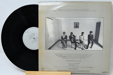 Vinyl record with its cover showing a black and white photo of five people sitting in a room.