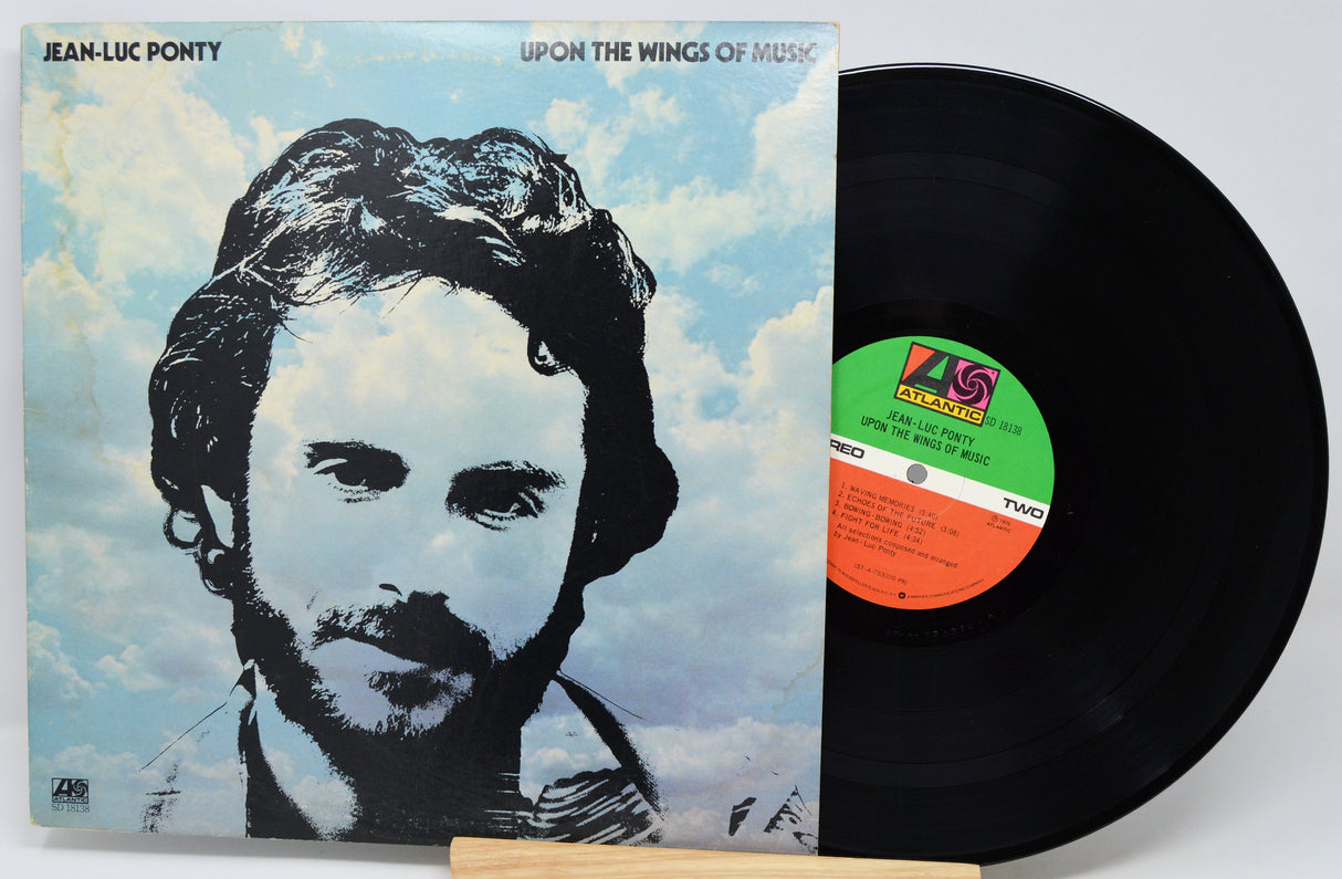 Jean-Luc Ponty 'Upon the Wings of Music' vinyl record LP with its illustrated album cover and a partially unsealed black record visible on a light background.
