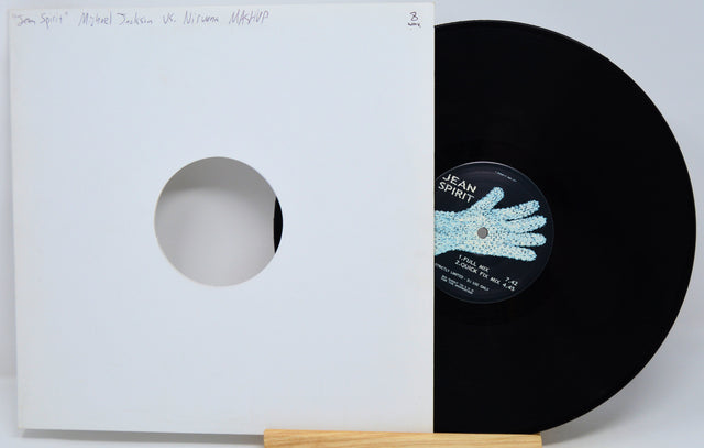 A black vinyl record partially pulled from a white sleeve with a circular cutout, displayed on a small wooden stand against a light gray background. The center label shows the text 'Jean Spirit'.