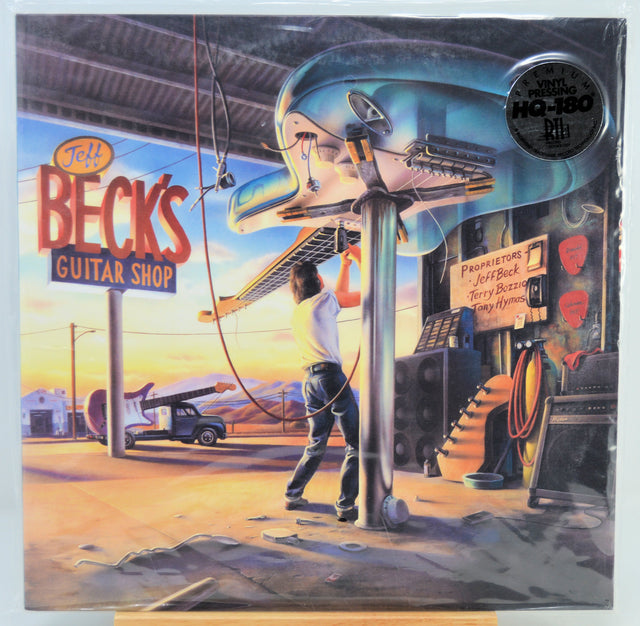 'Jeff Beck's Guitar Shop' vinyl LP album cover, showing a retro roadside scene with a large chrome guitar-shaped sign, a guitarist walking under it, and the album title 'Beck's Guitar Shop' in large red letters on the left.