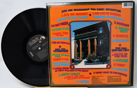 Vinyl record with its cover featuring text and a building image on an orange background.