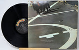 Vinyl record with cover featuring a group of people on a rooftop.