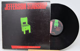 Jefferson Starship vinyl record album with the black LP partially pulled from the sleeve. The sleeve is black with bold red 'JEFFERSON STARSHIP' text and a bright green chair graphic, photographed against a light neutral background.